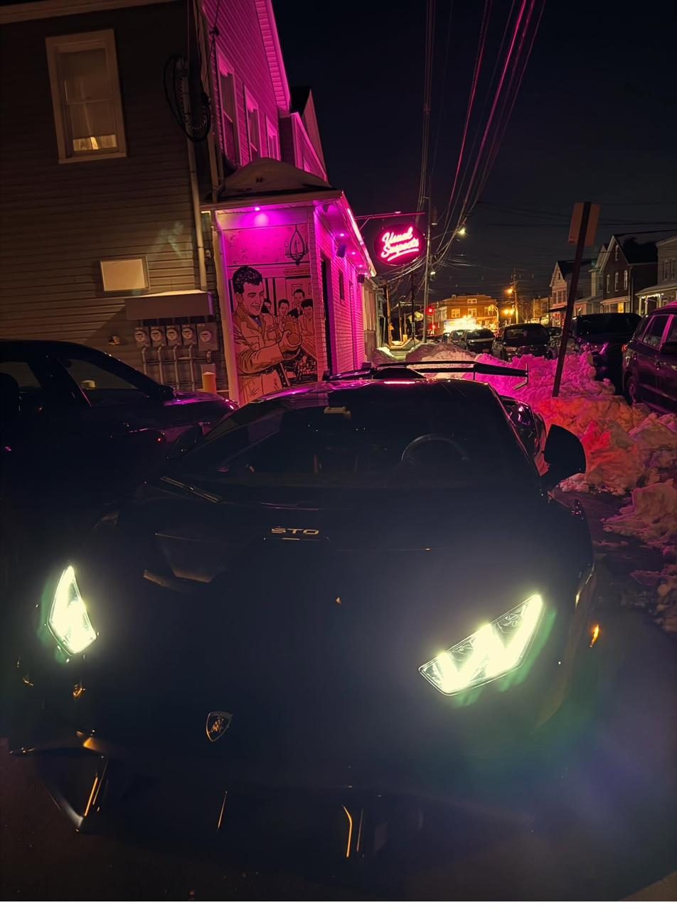 Lamborghini parked outside The Usual Suspects with the pink neon sign glowing