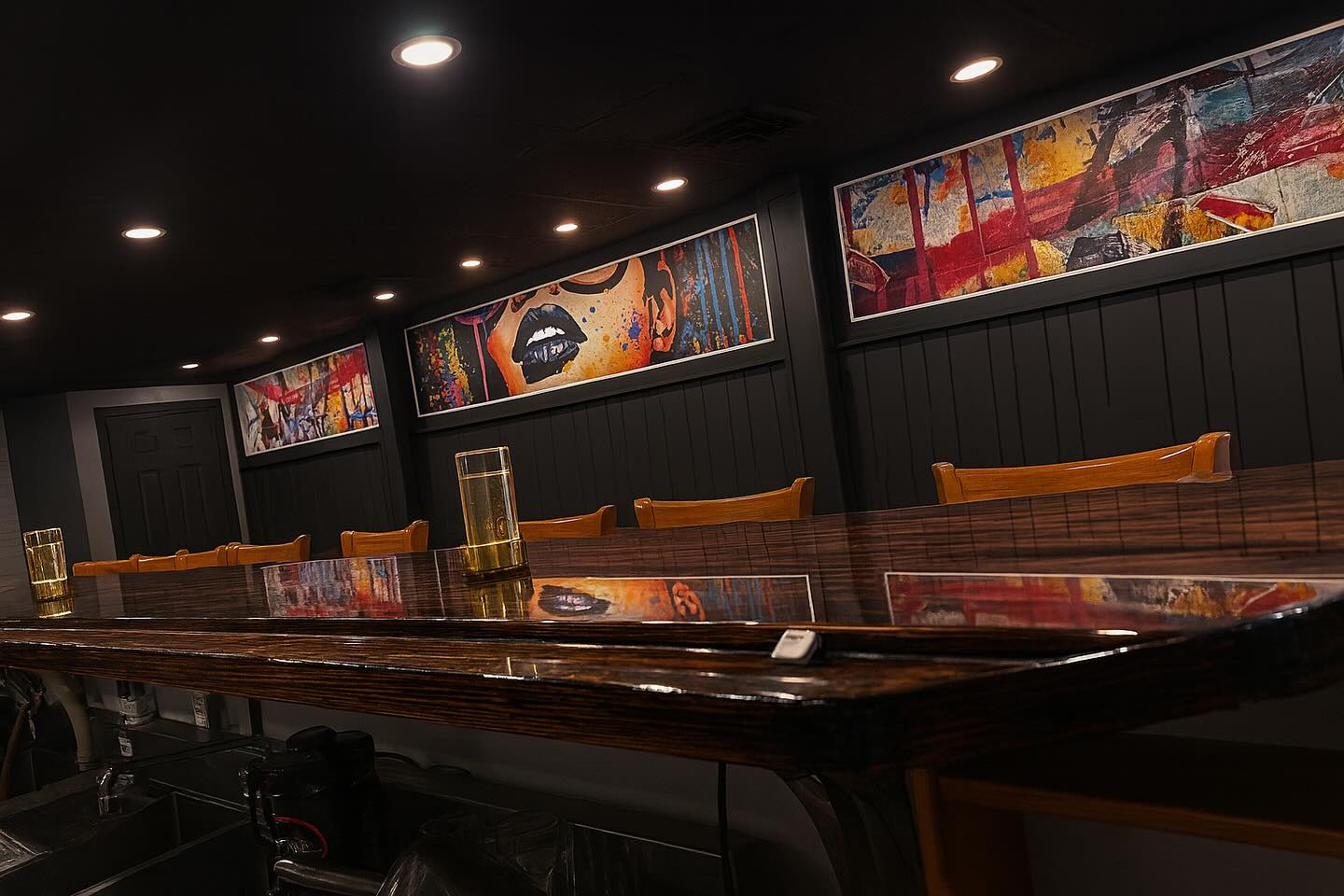 The Usual Suspects bar interior with colorful wall art and dark wood bar top — the private dining room space