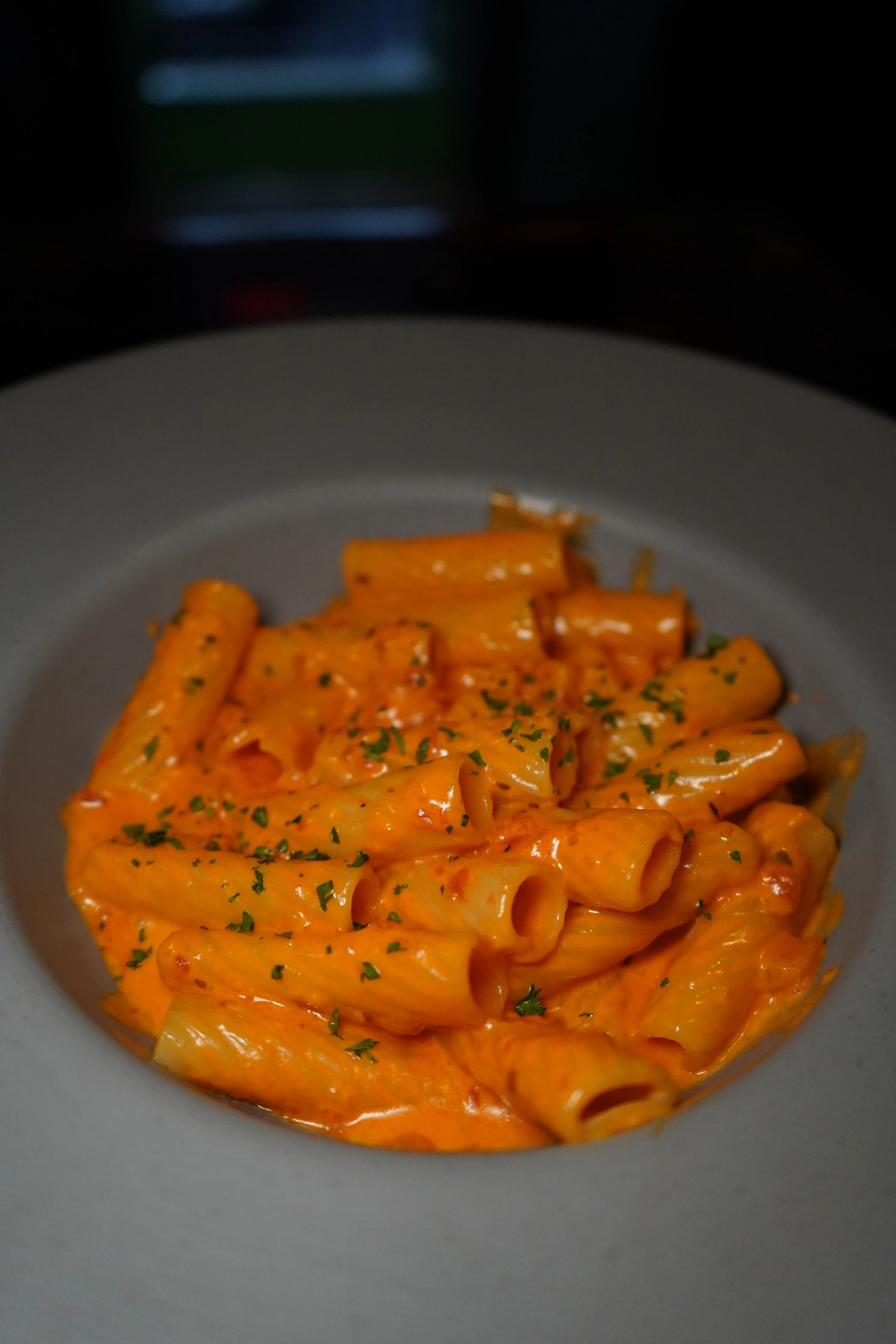 Rigatoni alla vodka with creamy orange sauce topped with fresh herbs